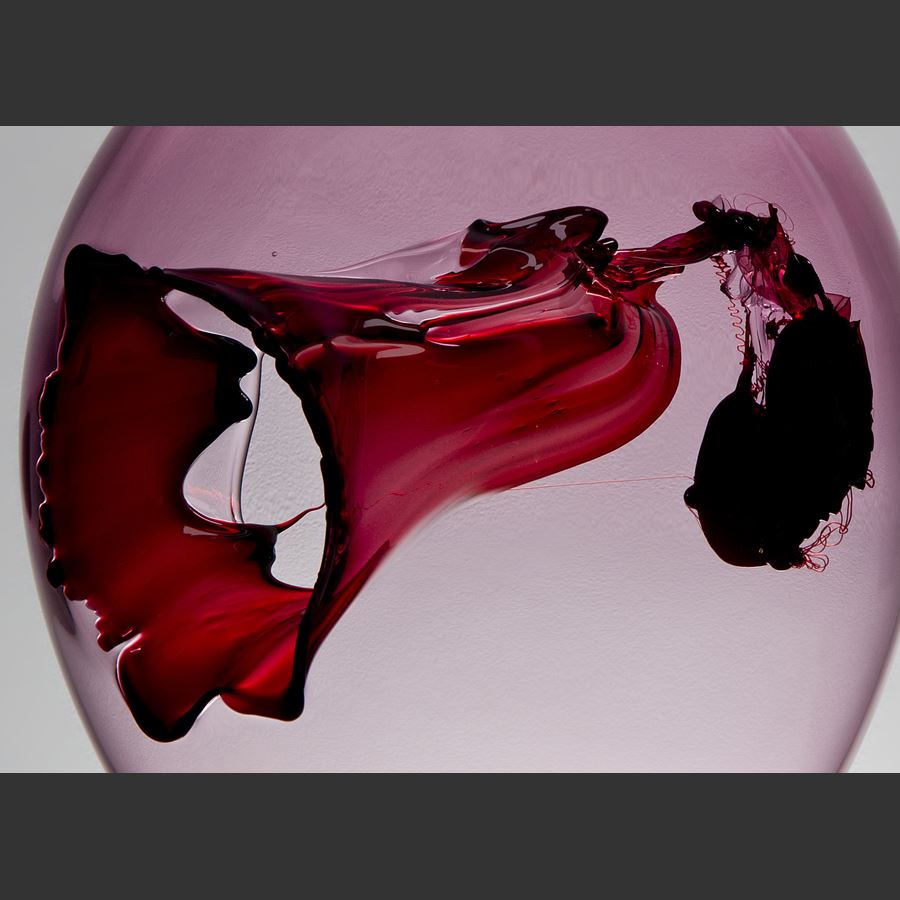 bubble shaped seethrough pink glass art sculpture with intricate interior red and black detail