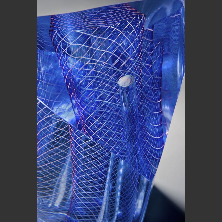 art glass sculpture with blue mesh pattern in dress shape caged in outer clear glass structure