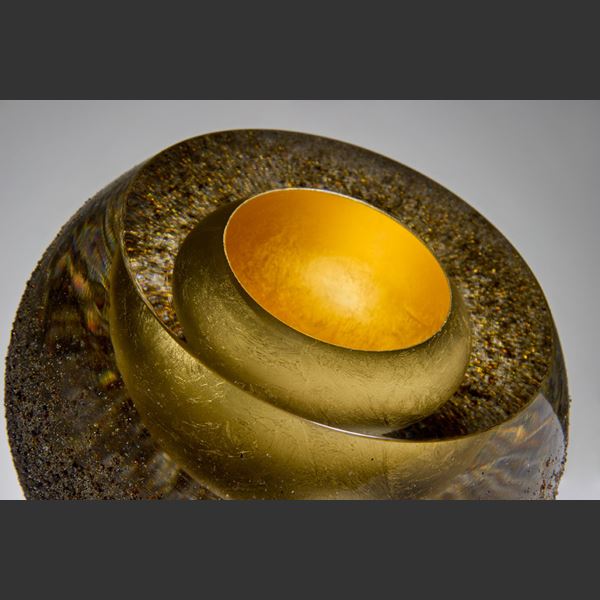 contemporary art glass sculpture of a sphere in earthy colours and layers showing golden core
