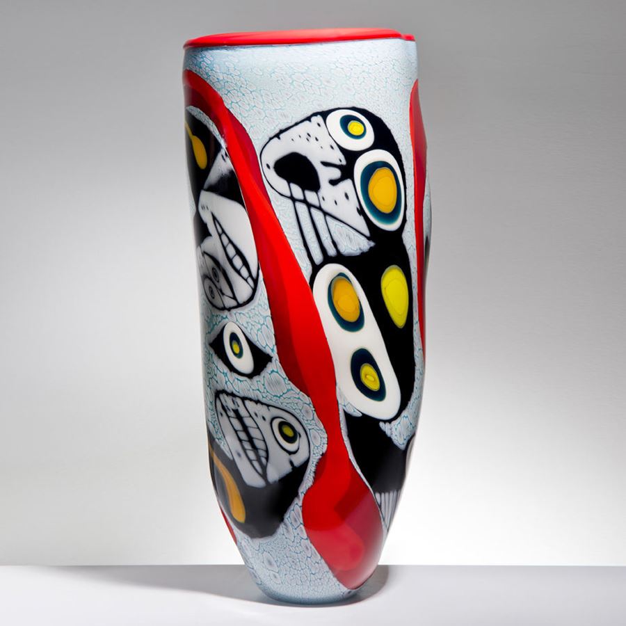 tall art glass vase with abstract faces painted on exterior in white red yellow and black