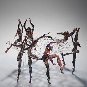 art glass sculpture of figures dancing round central clear glass pane