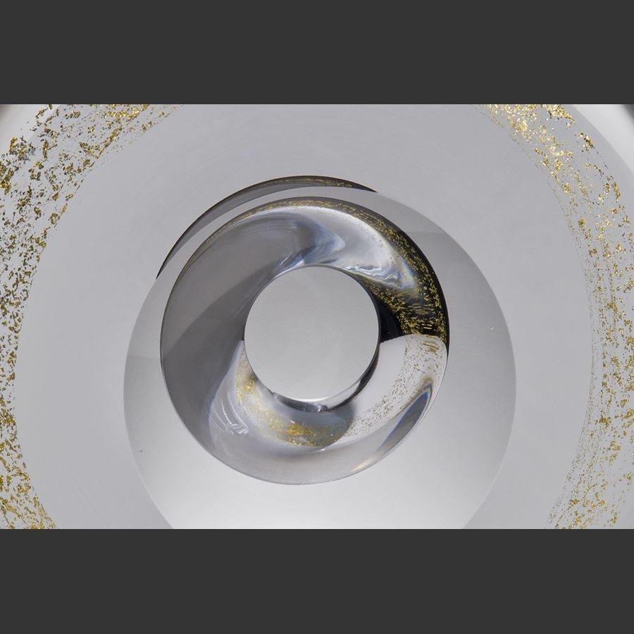 clear minimalist glass sculpture in the shape of a donut with spinkles of gold around the centre