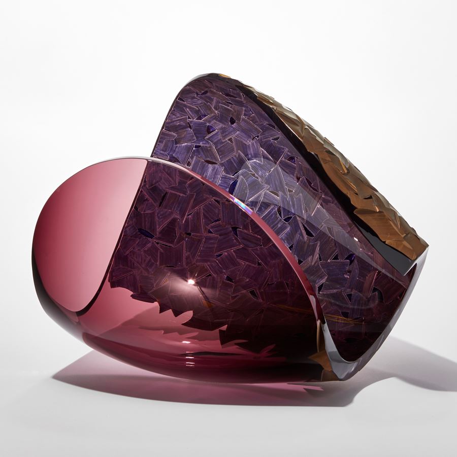 transparent aubergine ovoid with sweeping cut away section leaving a dramatic curved edge with one side covered in a deep incised cut organic pattern finished in gold hand made from glass