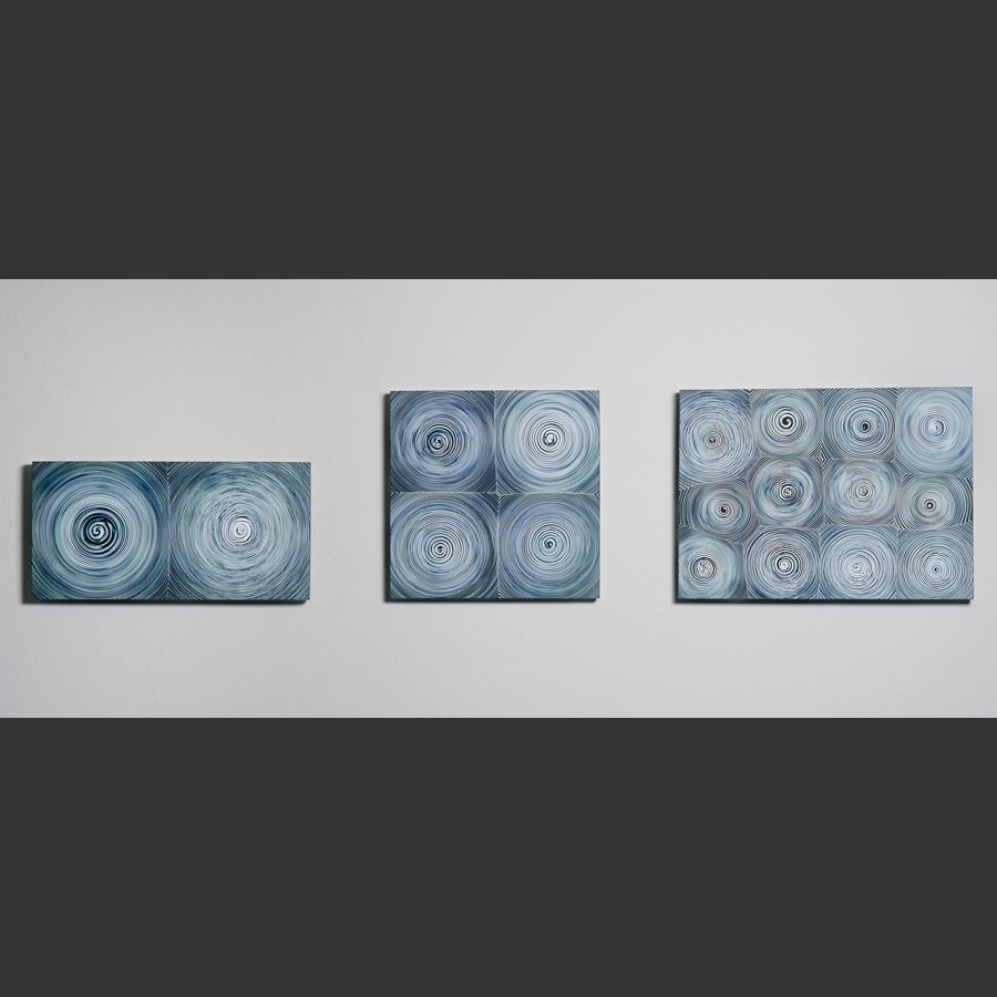 triptych of modern glass wall art with circular patterns in shades of blue and grey