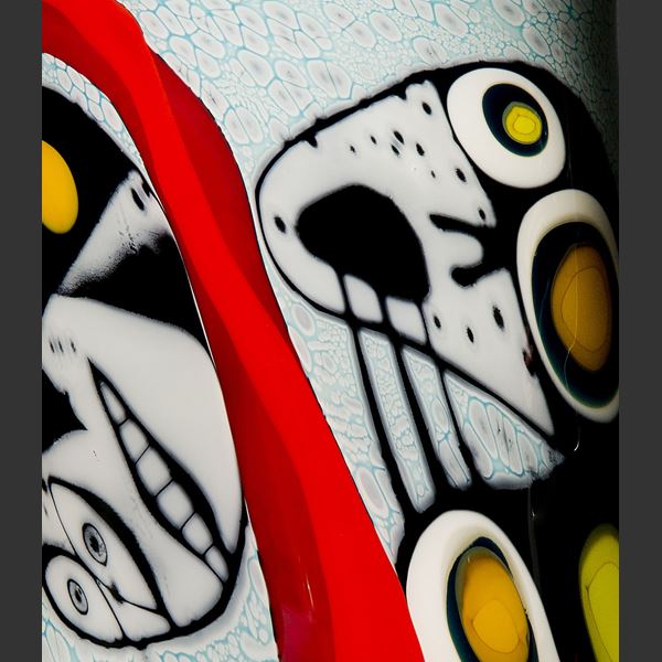 tall art glass vase with abstract faces painted on exterior in white red yellow and black