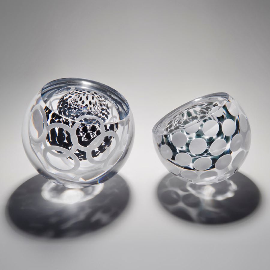 two small round glass artworks in clear glass with edged cut and circular pattern in white