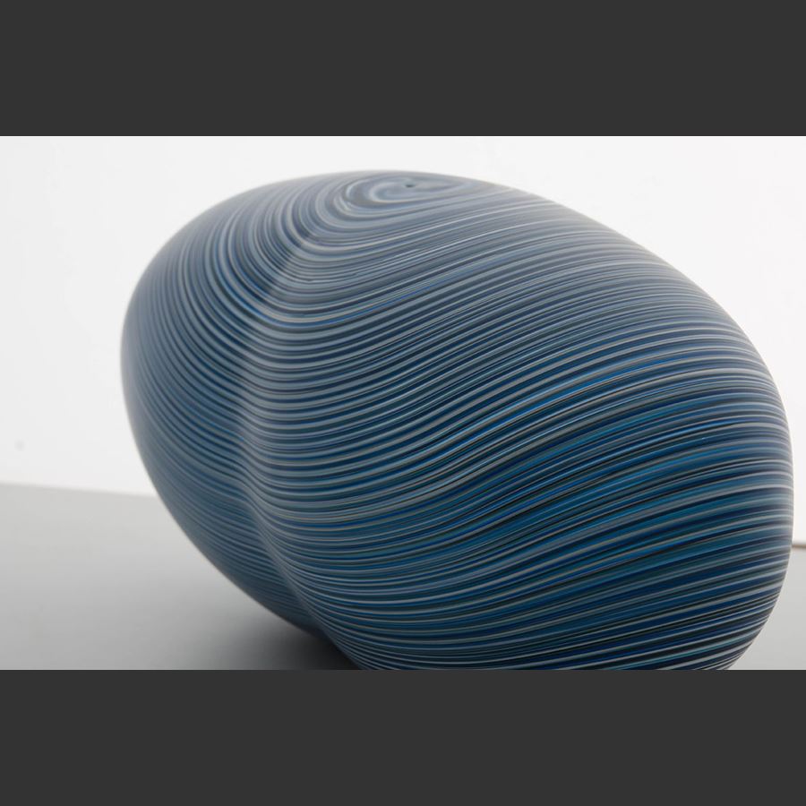rounded oval glass vessel sculpture with fine lined pattern in blue and grey 