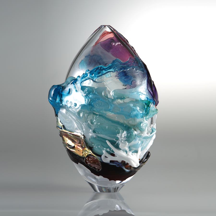 oval shaped clear glass sculpture with turquoise pink and brown splashes of colour