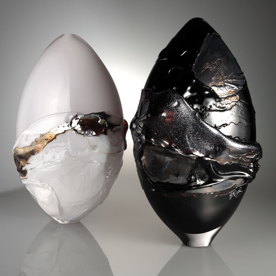 orb shaped art glass sculpture in white with black and gold splashes 