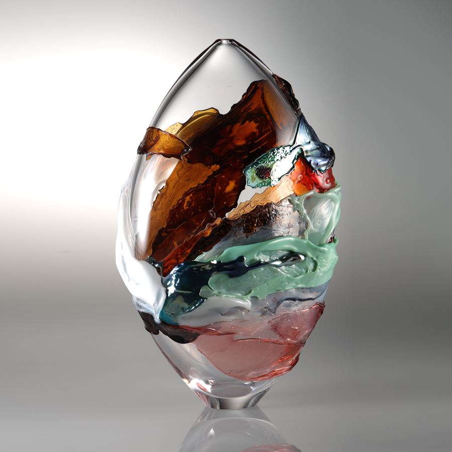 oval shaped blown clear glass vessel with splashes of dark orange light green and pink colour