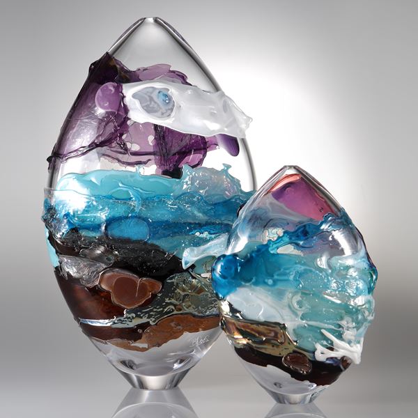 oval shaped handblown clear glass sculpture with purple blue and orange splashes