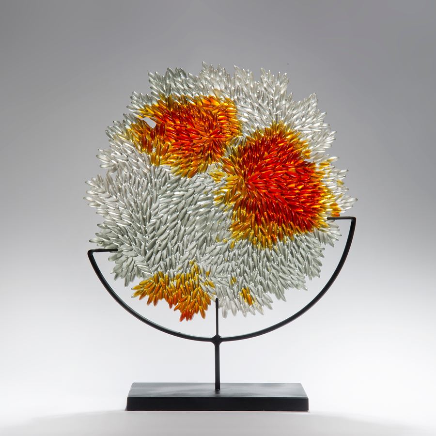 modern glass art sculpture of leaves in crystal and orange on metal base