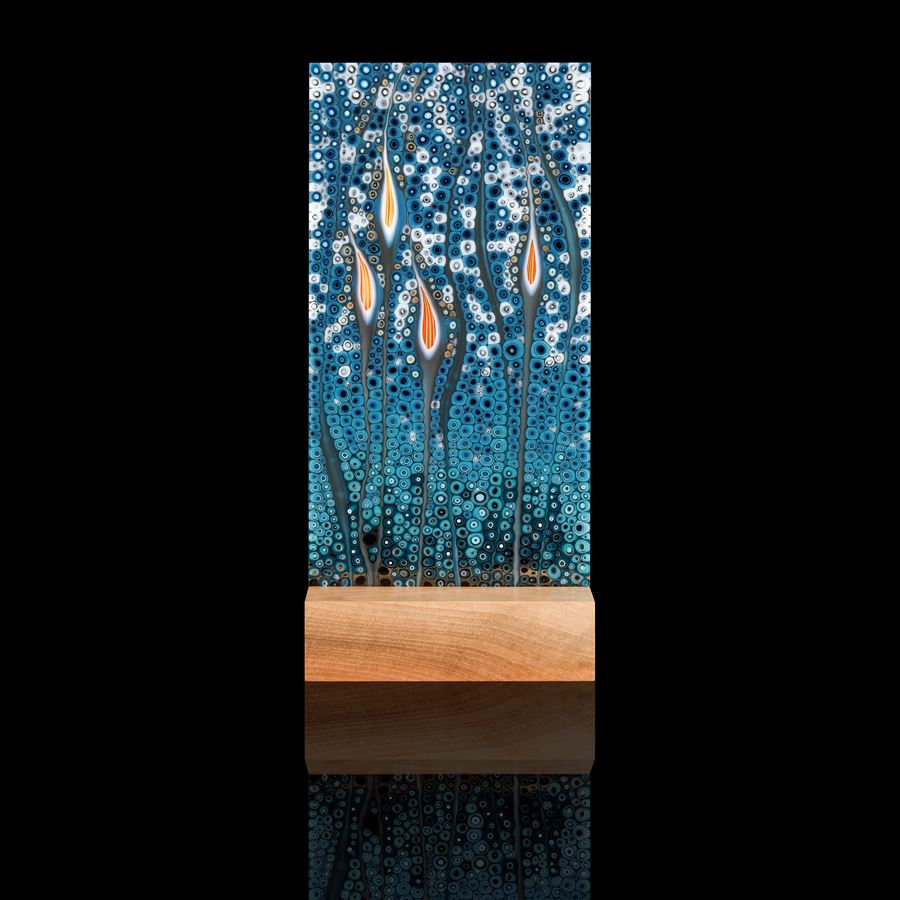 art glass sculptural panel in blue green and orange resting on wooden block