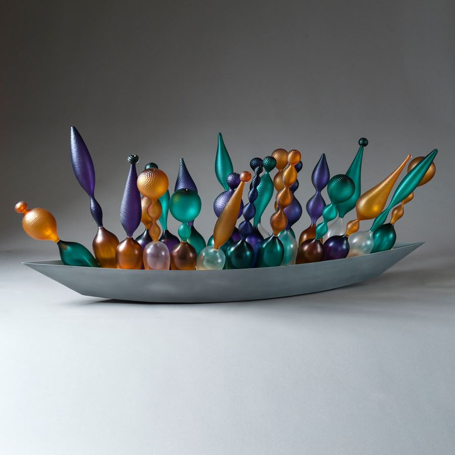 thin art glass sculpted objects in orange purple and green in long grey tray