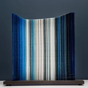 glass artwork resembling barcode in black blue and white on wooden base