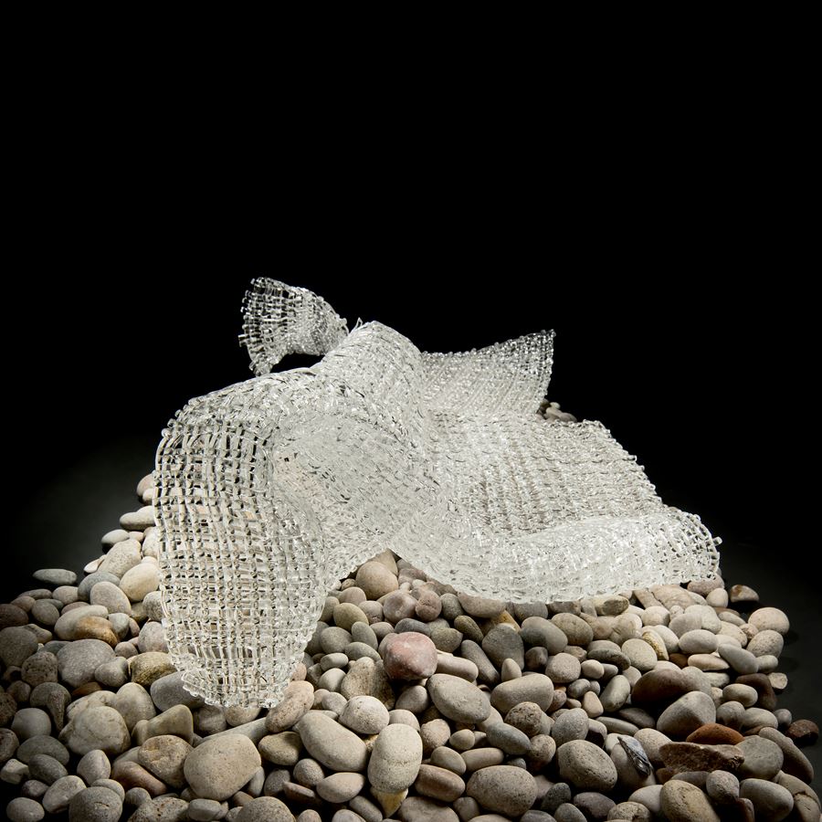 layered art glass sculpture resembling cloth on pebble base