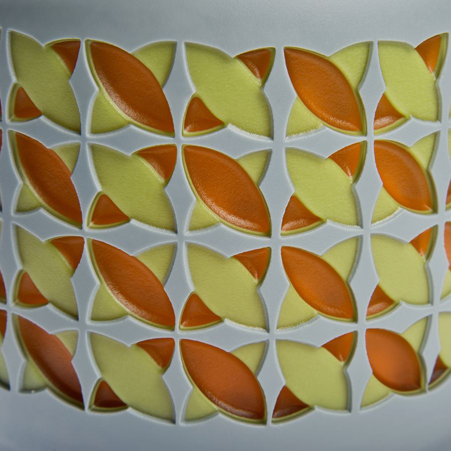 round cake shaped glass sculpture in grey with yellow and orange pattern