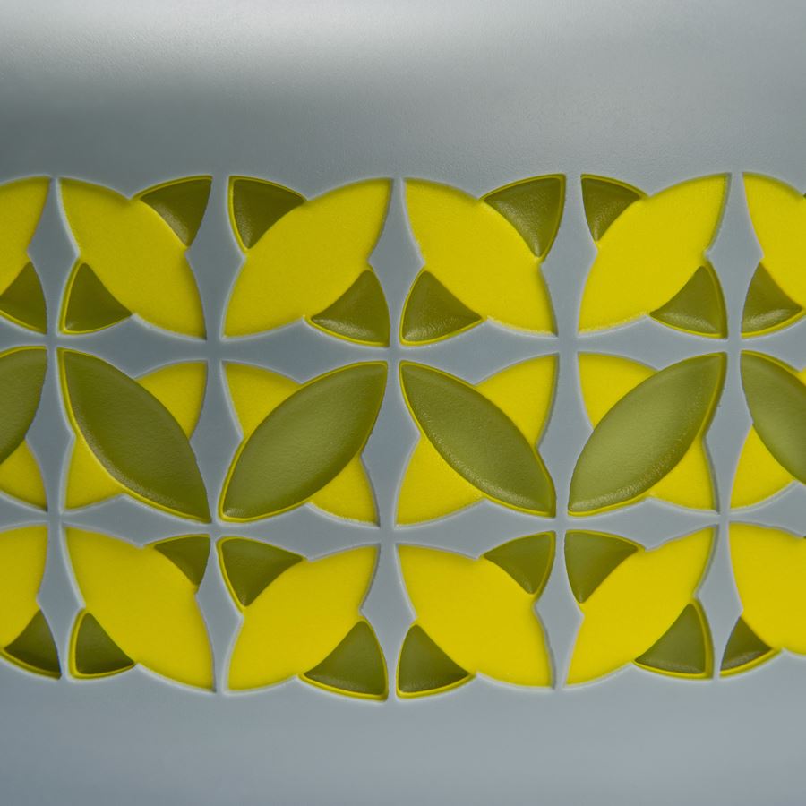 round cake shaped glass sculpture in grey with yellow and gren pattern