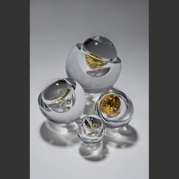 modern art glass sculpture of round object with hole in clear glass and platinum