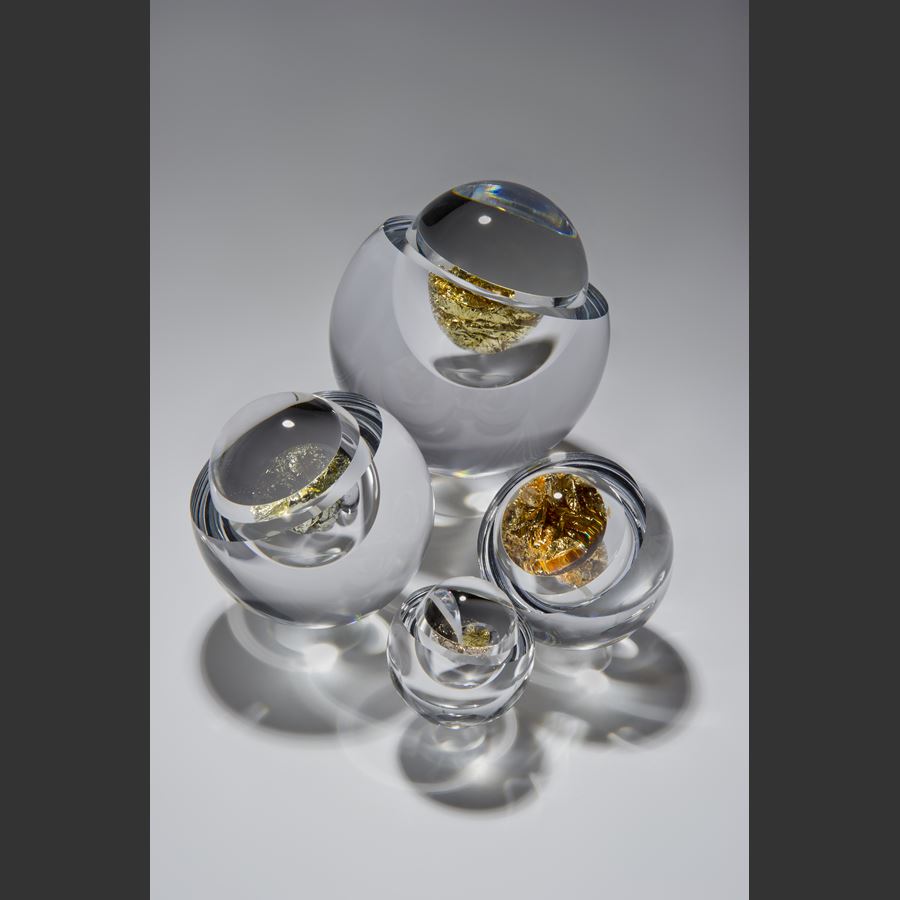 modern art glass sculpture of round object with hole in clear glass and platinum