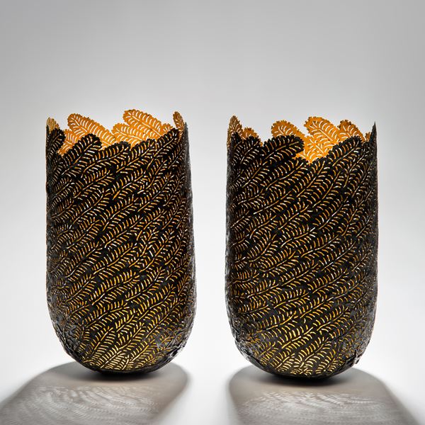 two sculpted open top vessels made from steel and gold cut leaf shapes arranged together