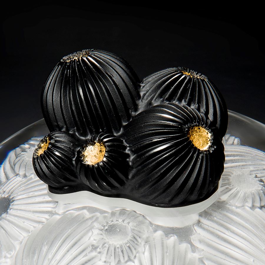 glass artwork of white star coral with round black berries in centre