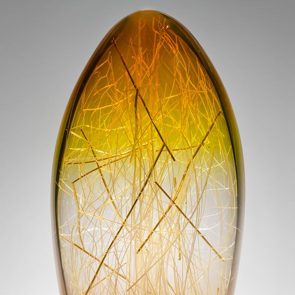 tall curved amber and coffee coloured glass sculpture with delicate nature-inspired internal structure 