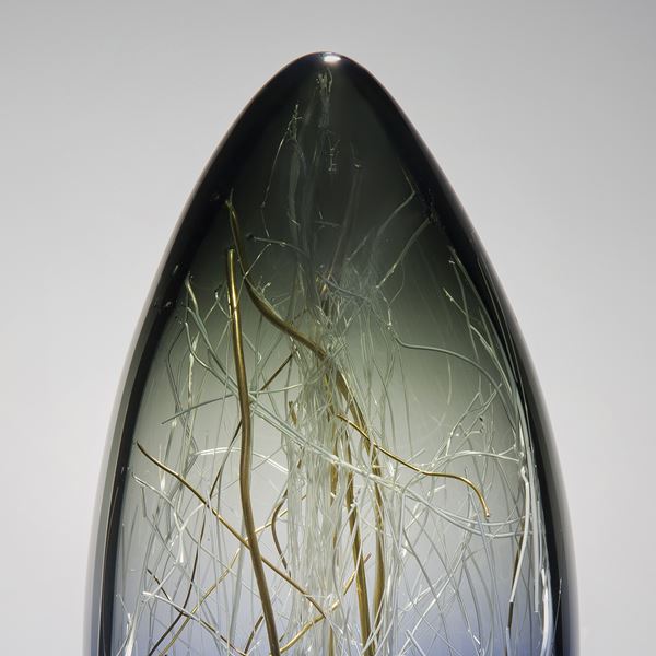 oblong shaped glass sculpture with wire interior in dark blue, green and gold colours