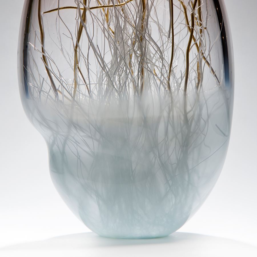 glass art vessel sculpture in grey and light blue with internal gold wire structure