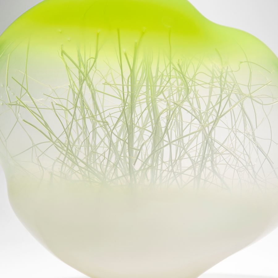 orb shaped glass art sculpture with internal tree branch like structure with white base and bright yellow top