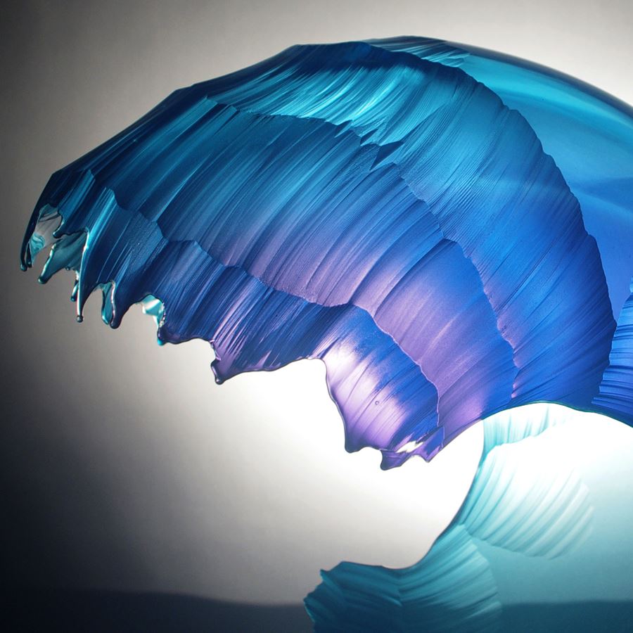 sculpted glass artwork in the shape of a wave with different shades of blue