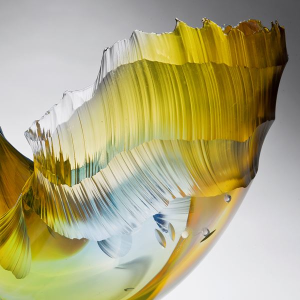 glass art sculpture in the shape of a wave in shades of yellow orange and blue