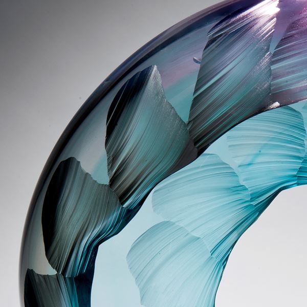 glass art sculpture in form of a wave in bright aqua blue with purple tint