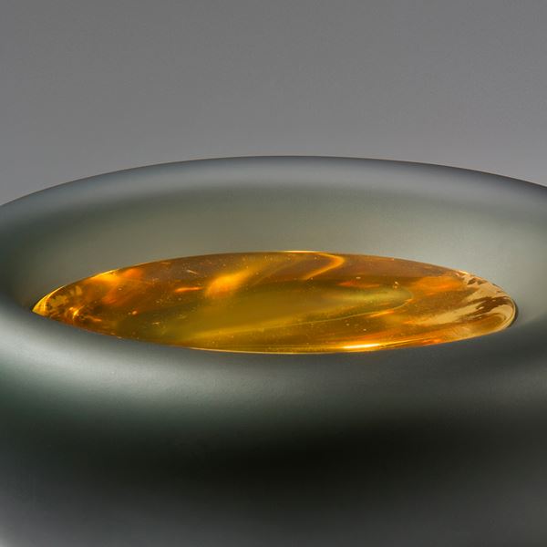 grey bowl glass and metal ornament with fiery yellow liquid like texture inside