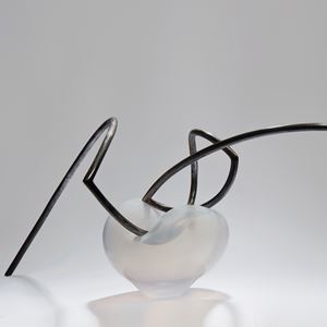 abstractly shaped pearl coloured glass dish with asymmetrical mangled thin black metal rod nestled in the centre