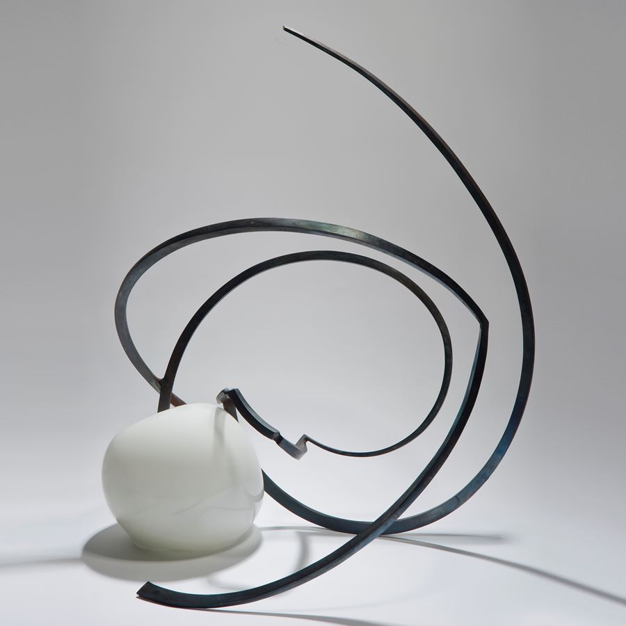 abstractly shaped pearl coloured glass sphere with asymmetrical mangled long thin black metal rod sprouting from the centre