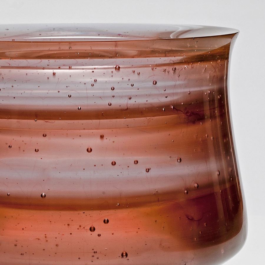 short sculpted glass vessel with open top in hues of brown with pattern resembling jupiter