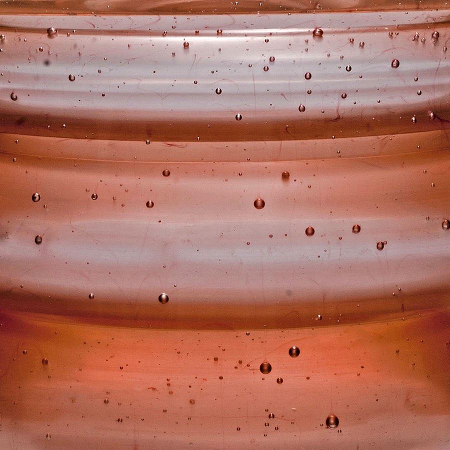 short sculpted glass vessel with open top in hues of brown with pattern resembling jupiter