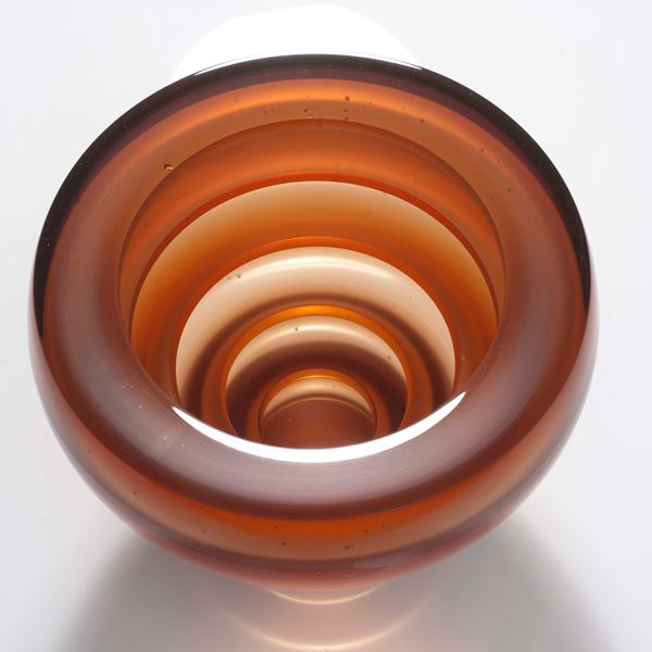 sculpted glass vessel with thin base and wide top with horizontal lined patters in orange shades