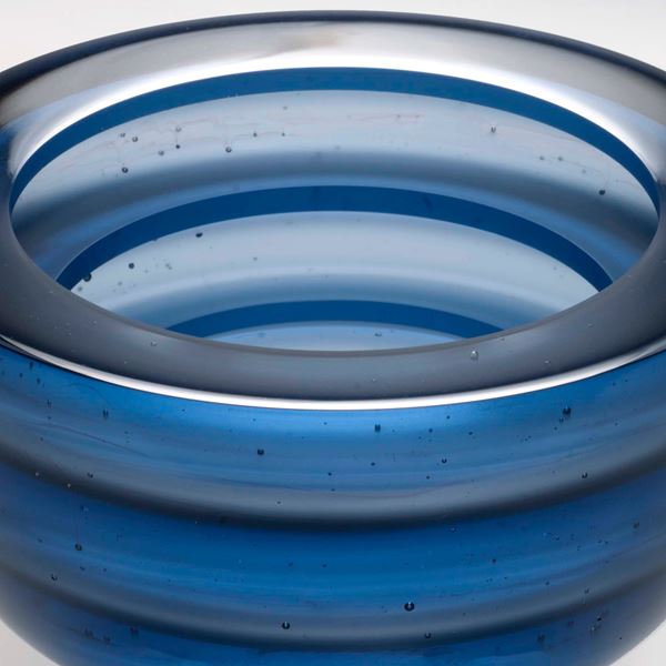 sculpted glass bowl with thin base in horizontal lined blue pattern