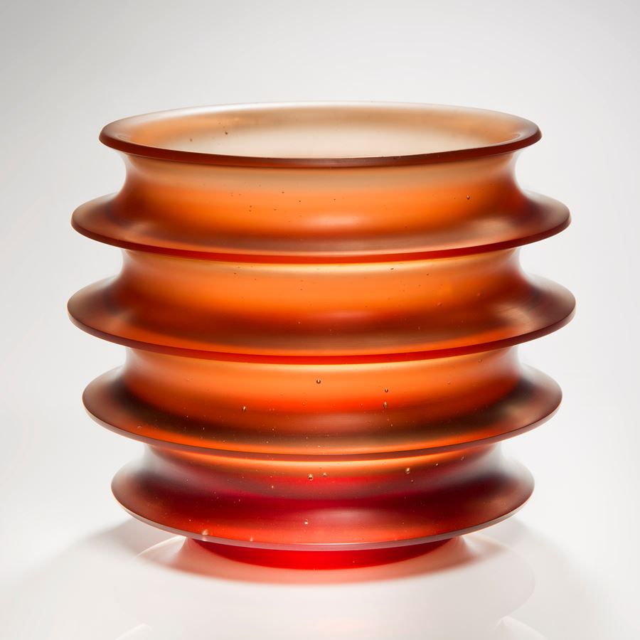 orange minimalist glass sculpture with five protruding rings