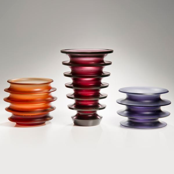 orange minimalist glass sculpture with five protruding rings