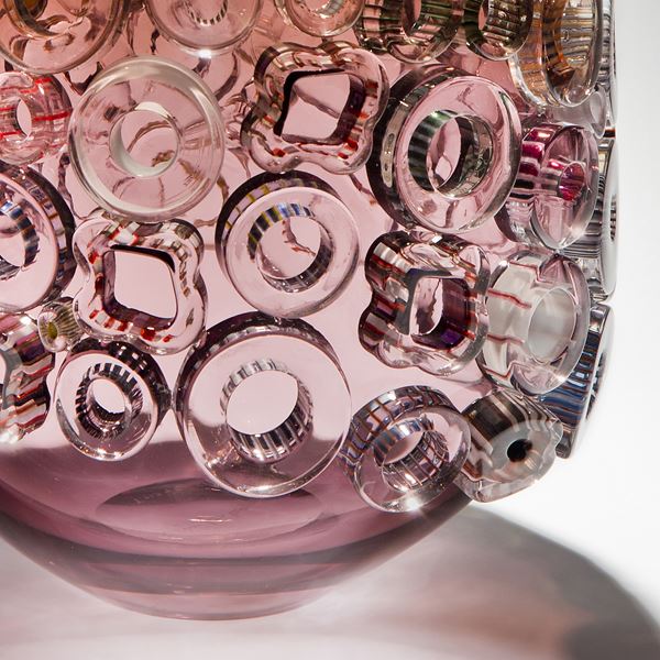 pink sculpted glass vase artwork with pink yellow and green circular patterns on exterior