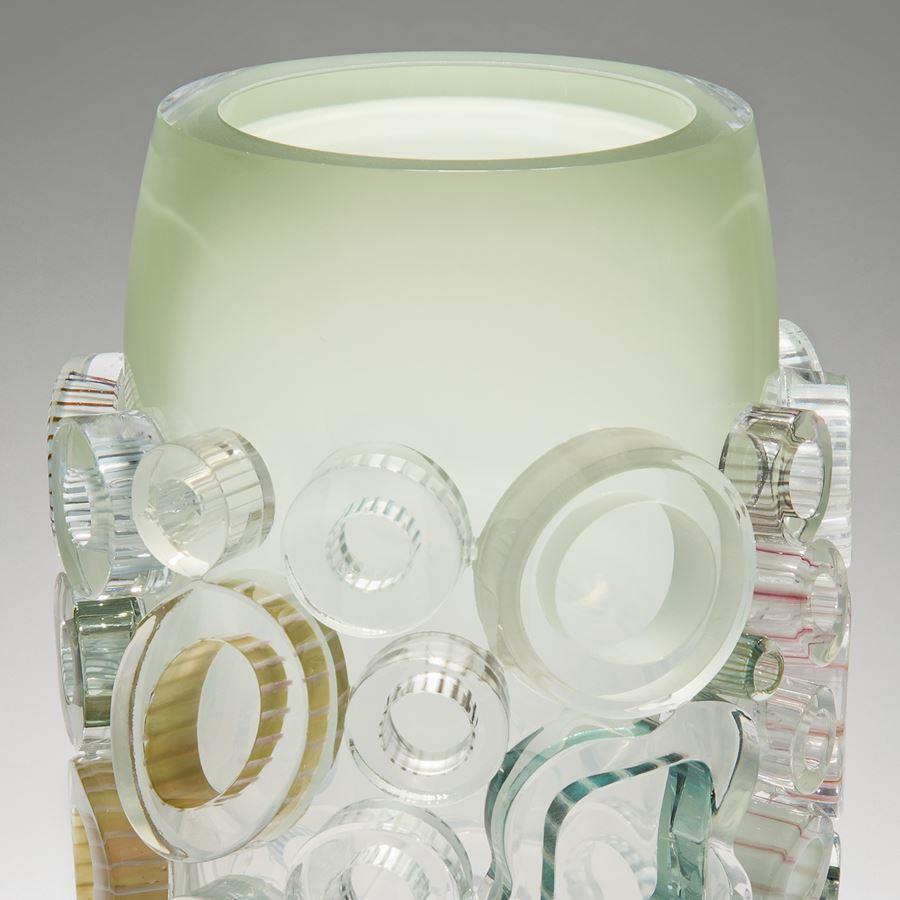 clear and green handblown glass vase sculpture with light coloured circular additions to the exterior