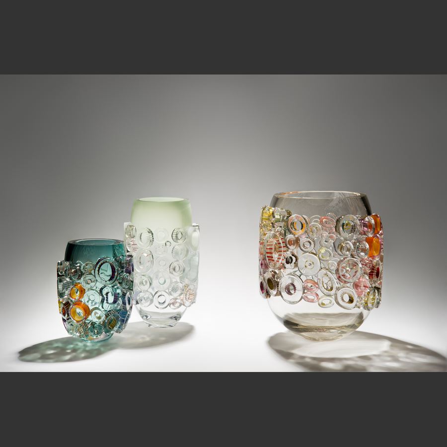 clear and green handblown glass vase sculpture with light coloured circular additions to the exterior