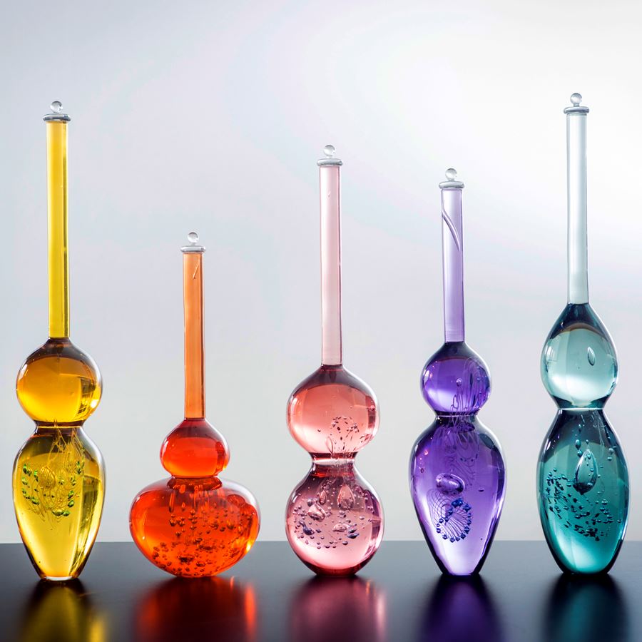 series of brightly coloured blown glass bottles with long thin necks