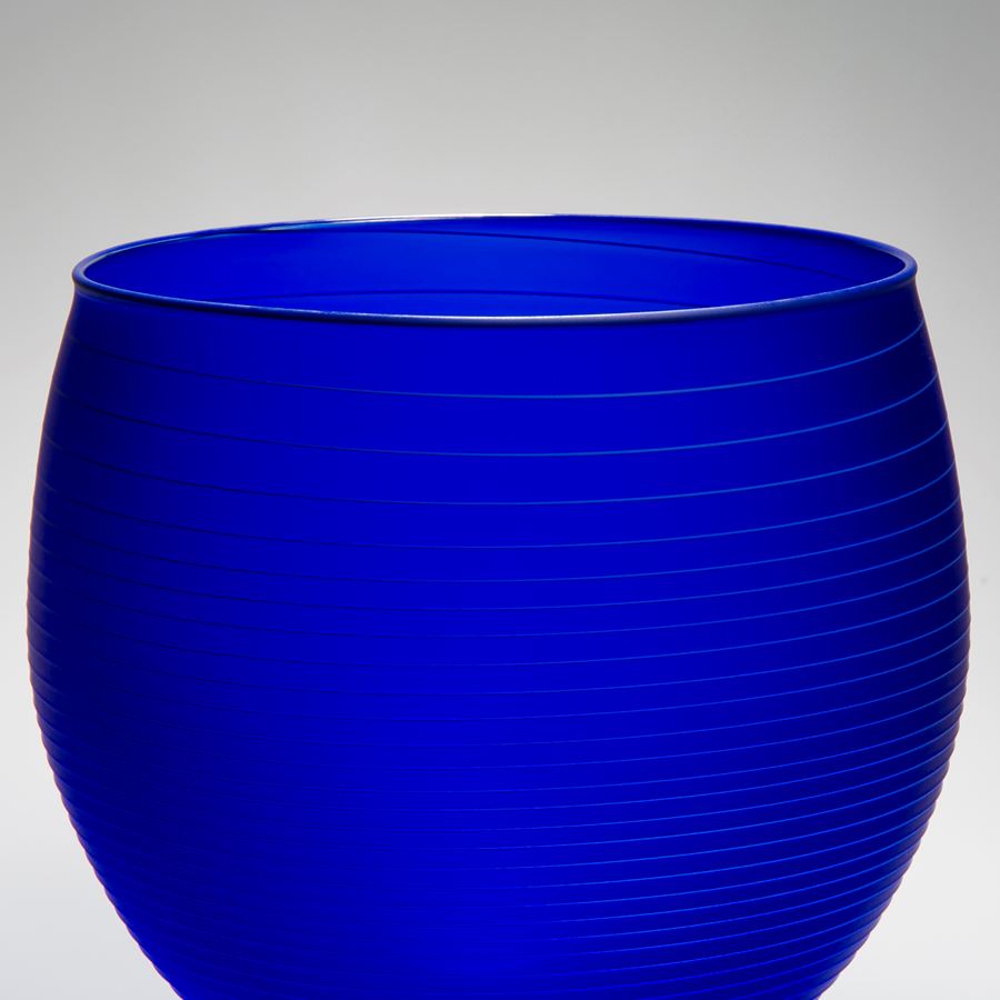 decorative glass bowl sculpture in deep blue with horizontal lines patterned throughout
