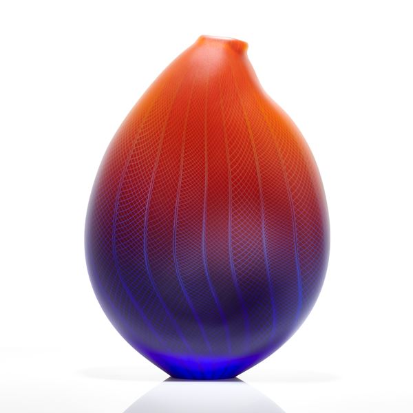 sculpted glass vessel in blue red and orange with small open top and lined and checked external engraved pattern