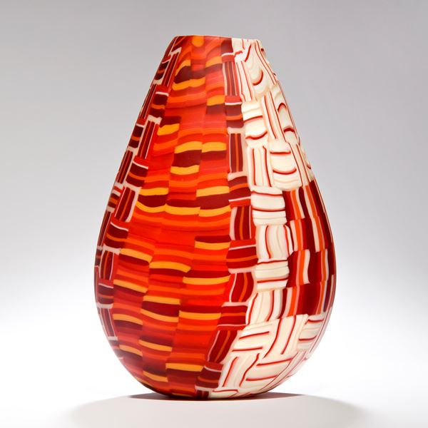 sculpted teardrop shaped glass vessel with crossing line pattern in white orange and burgandy