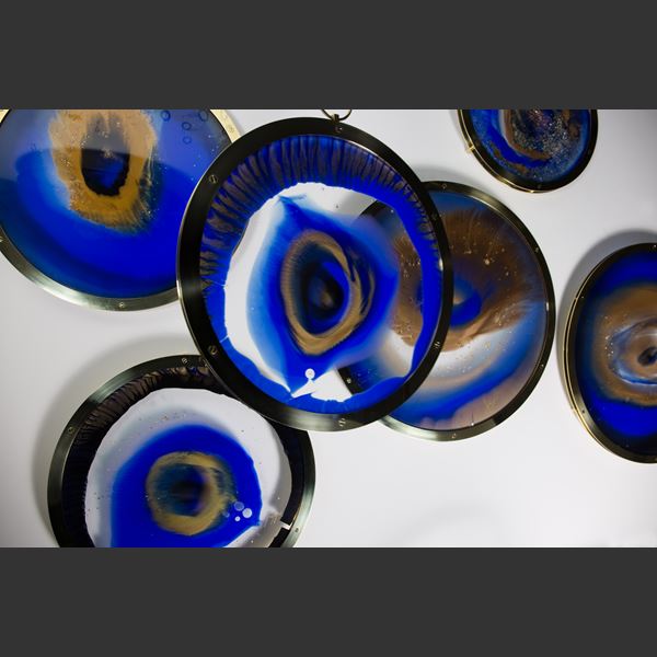 art glass sculpture of eye like shape in blue black and sand colours
